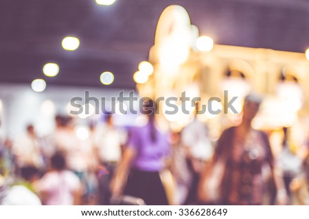 Blurred background: crowd of people in expo fair with bokeh light .