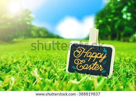 Happy easter on clip board on green grass field with blur park background,Holiday season