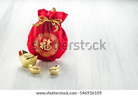 Chinese new year decoration,red fabric packet or ang pow with chinese style pattern and golden ingots on wood table top, Chinese Language mean Happiness,Leave space for add text