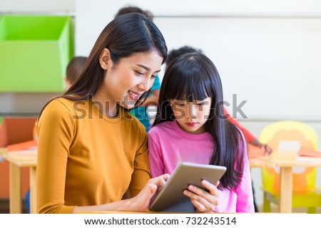 Asia woman teacher teach girl student with tablet computer in classroom at kindergarten preschool,Online education concept,e-learning