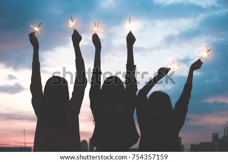 silhouette happy group of asia girl friends enjoy and play sparkler at rooftop party at evening sunset,Holiday celebration festive,teeage lifestyle,freedom and fun