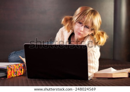 girl student preparing for exams in bed. On the bed of the book and a laptop.