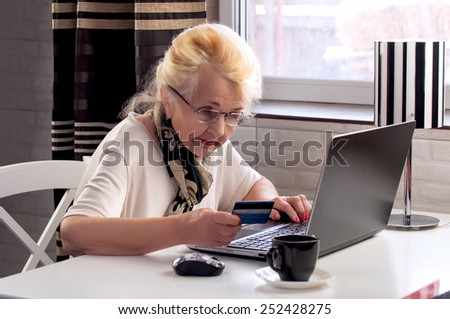 elderly lady makes a purchase through the Internet with a credit card
