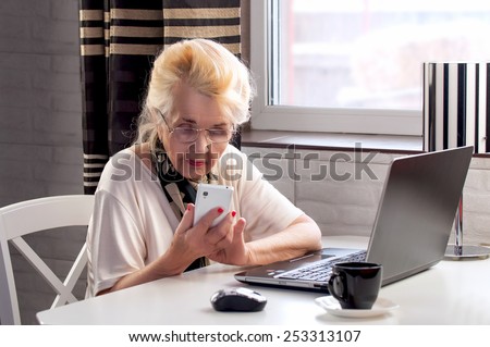 elderly lady talking on the phone and working with computer