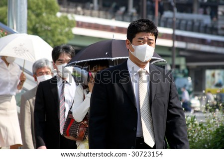 KOBE, JAPAN - MAY 20: People on the street wear face masks because of the outbreak of swine flu near Sannomiya JR station on May 20, 2009 in Kobe, Japan.