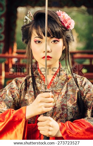 Beautiful korean woman or  geisha in kimono holding samurai sword near face