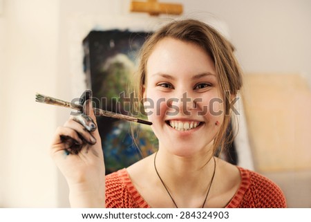 Portrait of beautiful woman artist with smile and positive emotion in home art studio