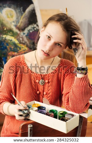 Portrait of beautiful woman artist with driming face in home art studio