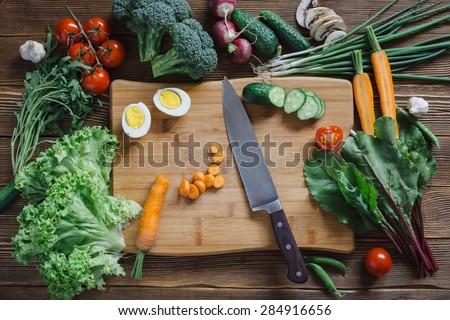 Healthy food and ingredients with tomato, arugula, carrots, beetroot, leaves, cucumber, onion, green, radish, mushrooms, garlic, broccoli, half, egg and peas on rustic wooden background, top view