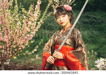Korean woman or geisha in kimono holding samurai sword near face