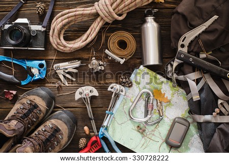 Equipment necessary for mountaineering and hiking on wooden background