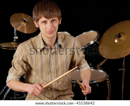Young musician playing drums isolated on black.