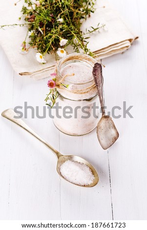 Himalayan pink salt in a glass jar and spoons on white wooden background. Selective focus