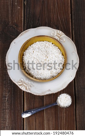 Short-grain rice in a rustic ceramic bowl on a dark wooden background. Top view
