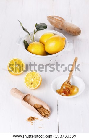 Group of organic lemons with honey and brown sugar over white wooden background
