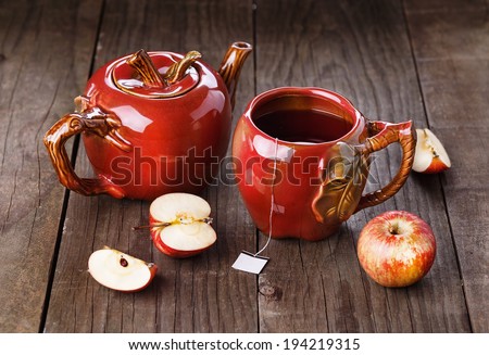 Apple tea in apple cup and teapot and apples over rustic wooden background