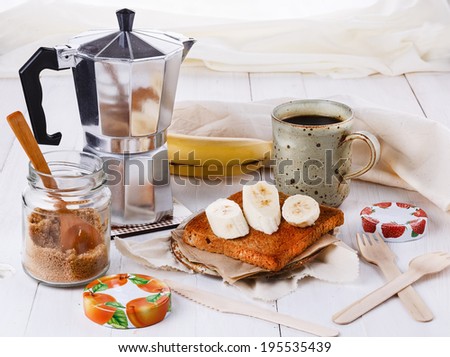 Breakfast with coffee and banana toast over white wooden background