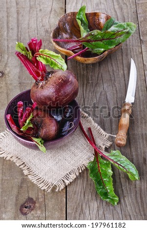 Organic beetroot and beetroot leaves over rustic wooden background