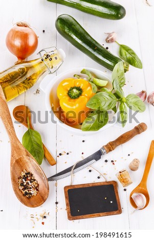 Food concept:  green and yellow organic vegetables, herbs and spices over white wooden background. Top view