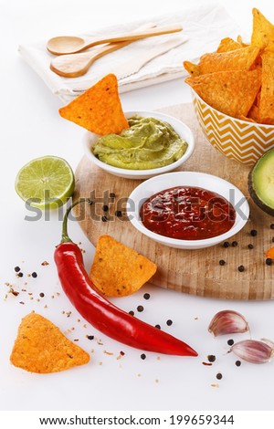 Mexican food concept: doritos, guacamole and salsa over white background