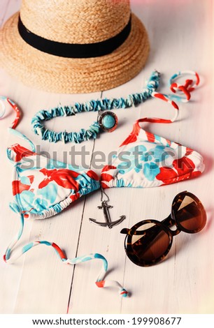 Retro style image of women summer fashion: bikini, straw hat and accessories over white wooden background. Selective focus, shallow DoF, vintage effect filters, light leak effect