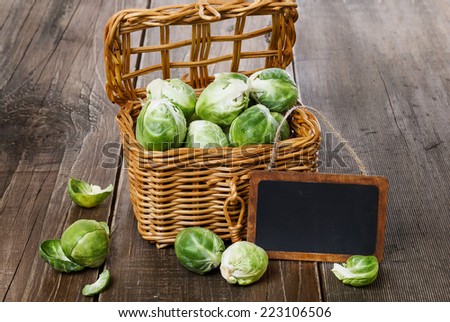 Brussels sprouts in a woven basket and tag over rustic wooden background