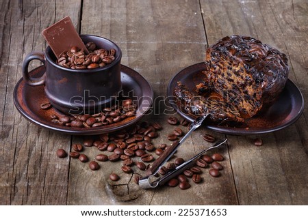 Roasted coffee beans in a brown ceramic cup and fruit cake over rustic wooden background. Selective focus