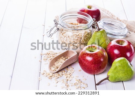 Fresh apples and pears and rolled oats over white wooden background. Selective focus, shallow DoF