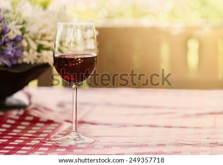 Single glass of red wine over natural background with hazy sunlight and bokeh. Copy space, selective focus, shallow Depth of field