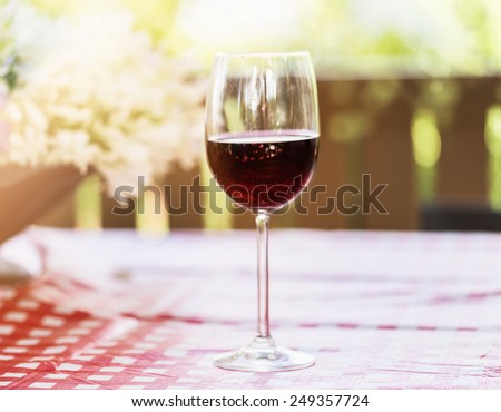 Single glass of red wine over natural background with hazy sunlight and bokeh. Selective focus, shallow Depth of field