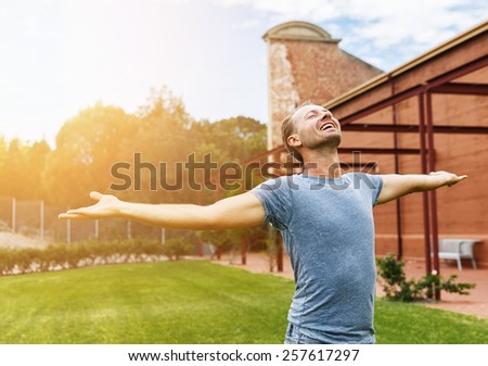 Happy man standing in a city garden with arms spread open. Selective focus