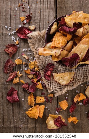 Top view of healthy vegetable beetroot, sweet potato and white sweet potato chips over rustic background