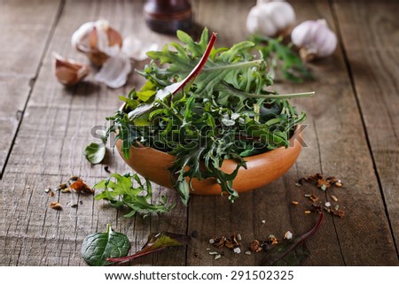 Leafy green mix of kale, spinach, baby beetroot leaves over rustic wooden background