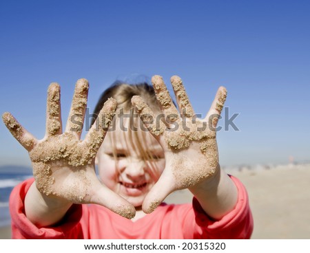 girl with hands covered with sand, focus on hands.