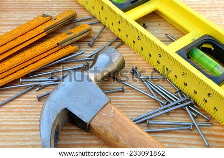 Claw hammer, carpenter meter, water-level and nails on wooden desk background