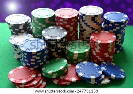 Red, blue, green, white and black poker chips pile on green table