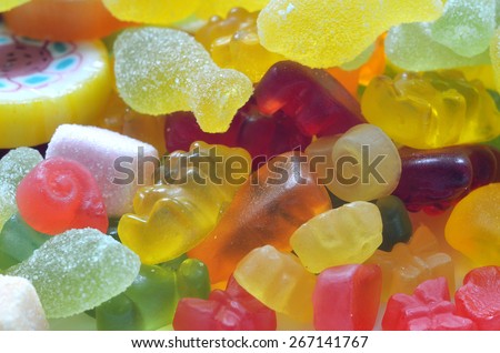 Macro detail of lollipop, gummy bears and sour candy on colored smarties background