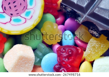 Macro detail of lollipop, gummy bears, chocolate and sour candy on colored smarties background