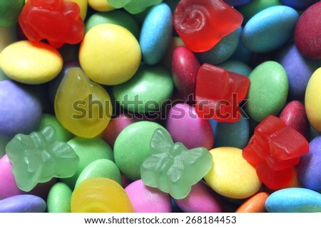 Macro detail of pile of colored smarties and candy shaped like butterfly background