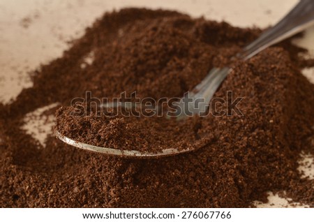 Close-up detail of spoon in dark brown powder of coffee
