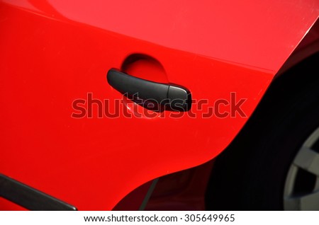 Detail of a car door in red metallic with black handle