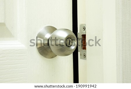 round stainless steel door knob of restroom on white wooden door