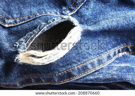 Blue denim jeans in dark color tear up surface below backside pocket in the scene present the old damaging fabric damaged detail of texture background.