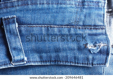 Blue denim jeans in bright color in the scene present the belt loops and button hole this denim look the old damaging fabric that shown detail of texture background.