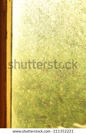 Dirty window glass on wooden frame in brown color photo caption from late afternoon time appear the orange color tone warm natural light in the scene.