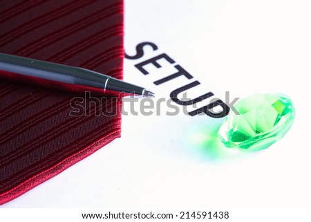 Red color of necktie close up photo in the scene with the white paper color printed the word set up put beside show the pattern and texture fabric of  necktie represent the formalwear business look.
