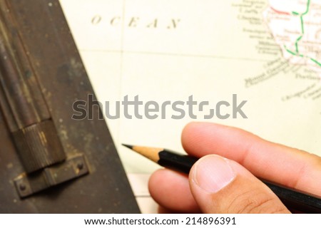 Old  and vintage paper map  with pencil in man hand and  old brass slide rule putting on it represent the detail of city name and destination.