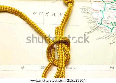 Gold color rope cable with simple knot  put on old  and vintage paper map represent the detail of city name and destination.