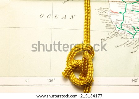 Gold color rope cable with simple knot put on old  and vintage paper map represent the detail of city name and destination.