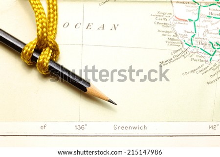 Gold color rope cable with simple knot and pencil put on old  and vintage paper map represent the detail of city name and destination.